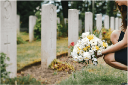 Woman placing flowers next to headstone